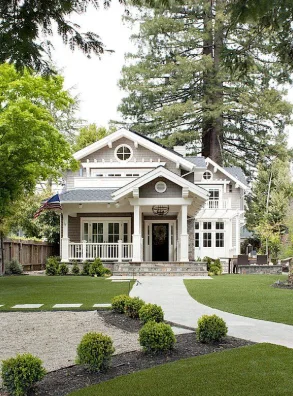 A craftsman-style home with a covered porch and mature front-yard trees